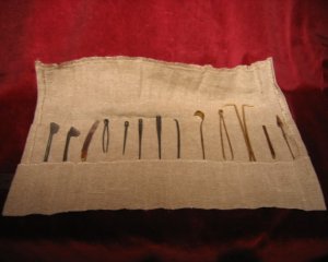 A replica of Roman surgical instruments in a cloth roll, AD50. 13 instruments made of brass and steel. (The Old Operating Theatre Museum)